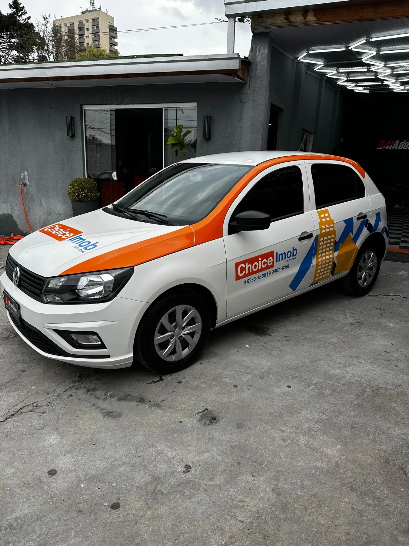 Volkswagen Gol branco com plotagem Choice Imob laranja e azul