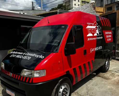 Van vermelha e preta plotada da JM Reformas e Construção