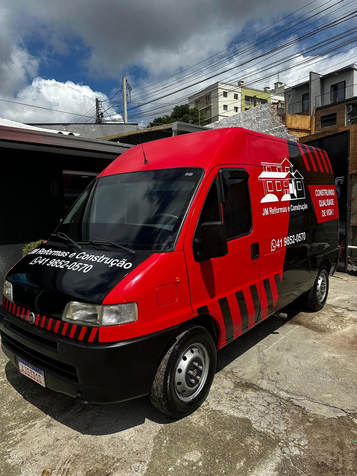 Van vermelha e preta plotada da JM Reformas e Construção