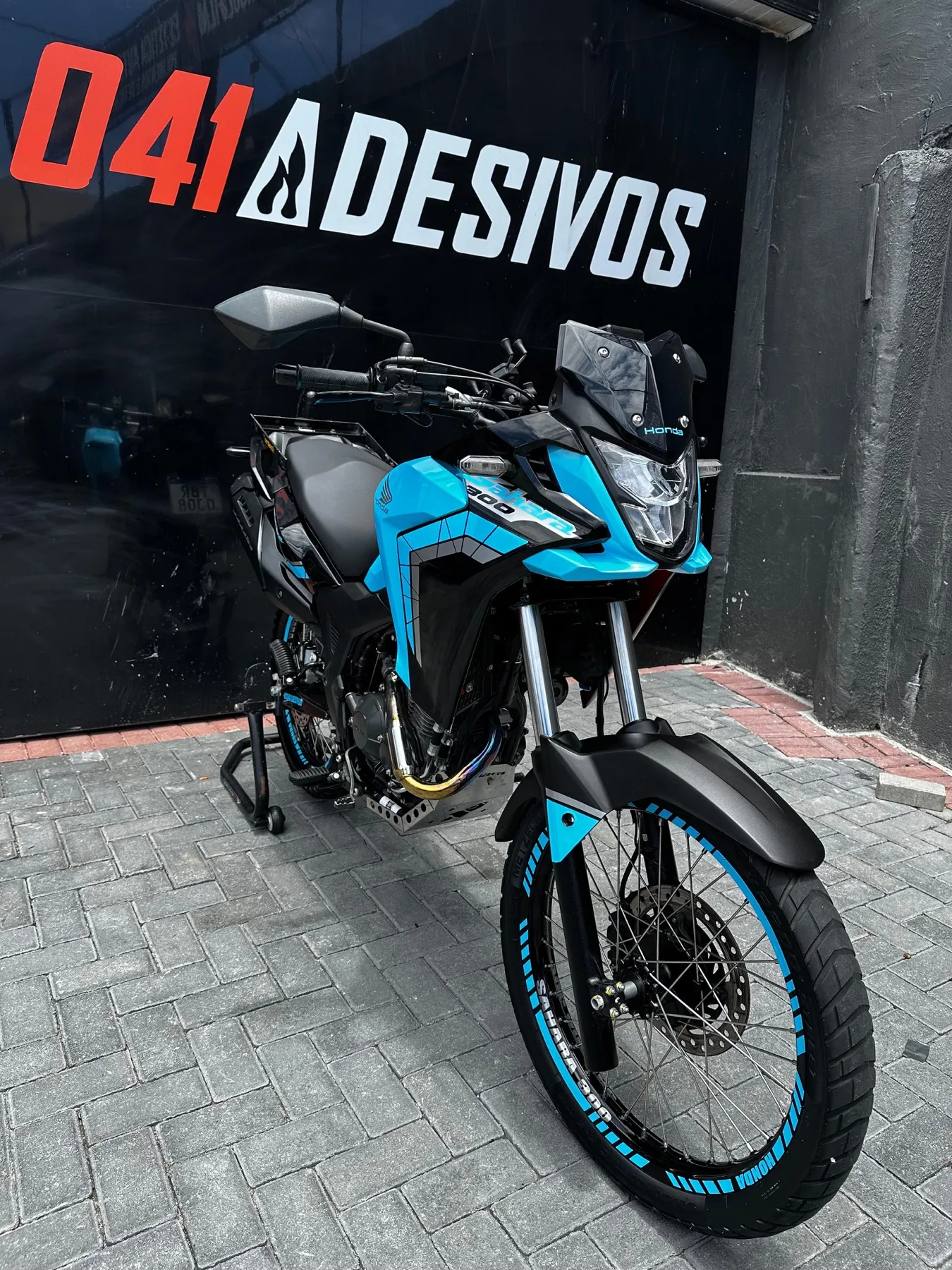 Moto trail Honda azul claro com adesivagem nas rodas