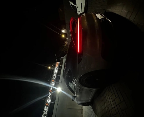 SUV escuro à noite com lanterna em LED acesa em frente à loja