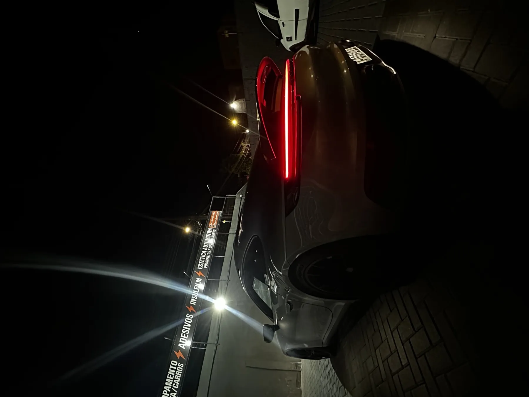 SUV escuro à noite com lanterna em LED acesa em frente à loja