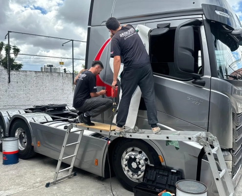 Equipe aplicando película em cavalo mecânico Volvo FH cinza