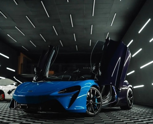 McLaren Artura azul com portas borboleta em estúdio escuro