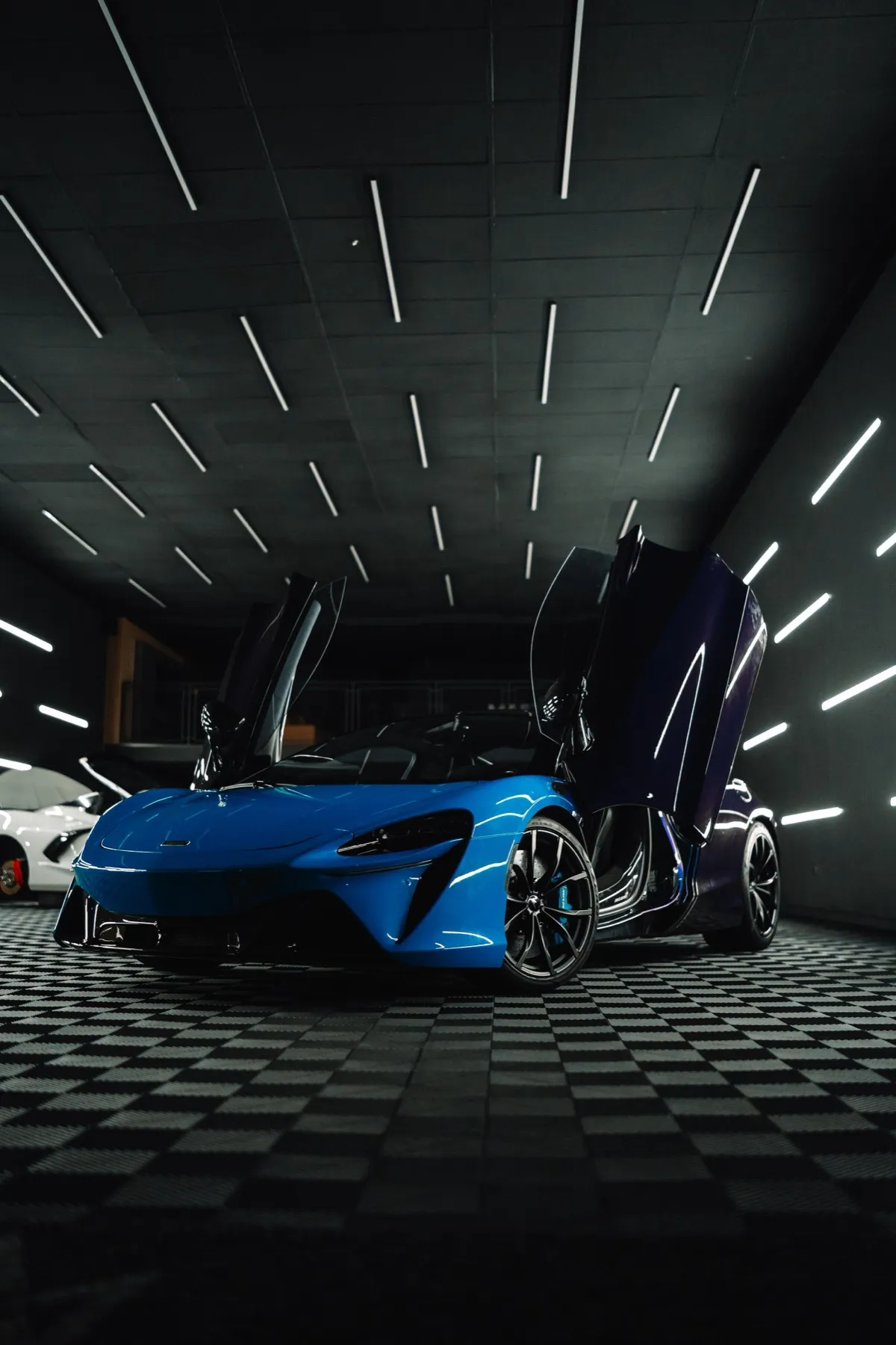 McLaren Artura azul com portas borboleta em estúdio escuro