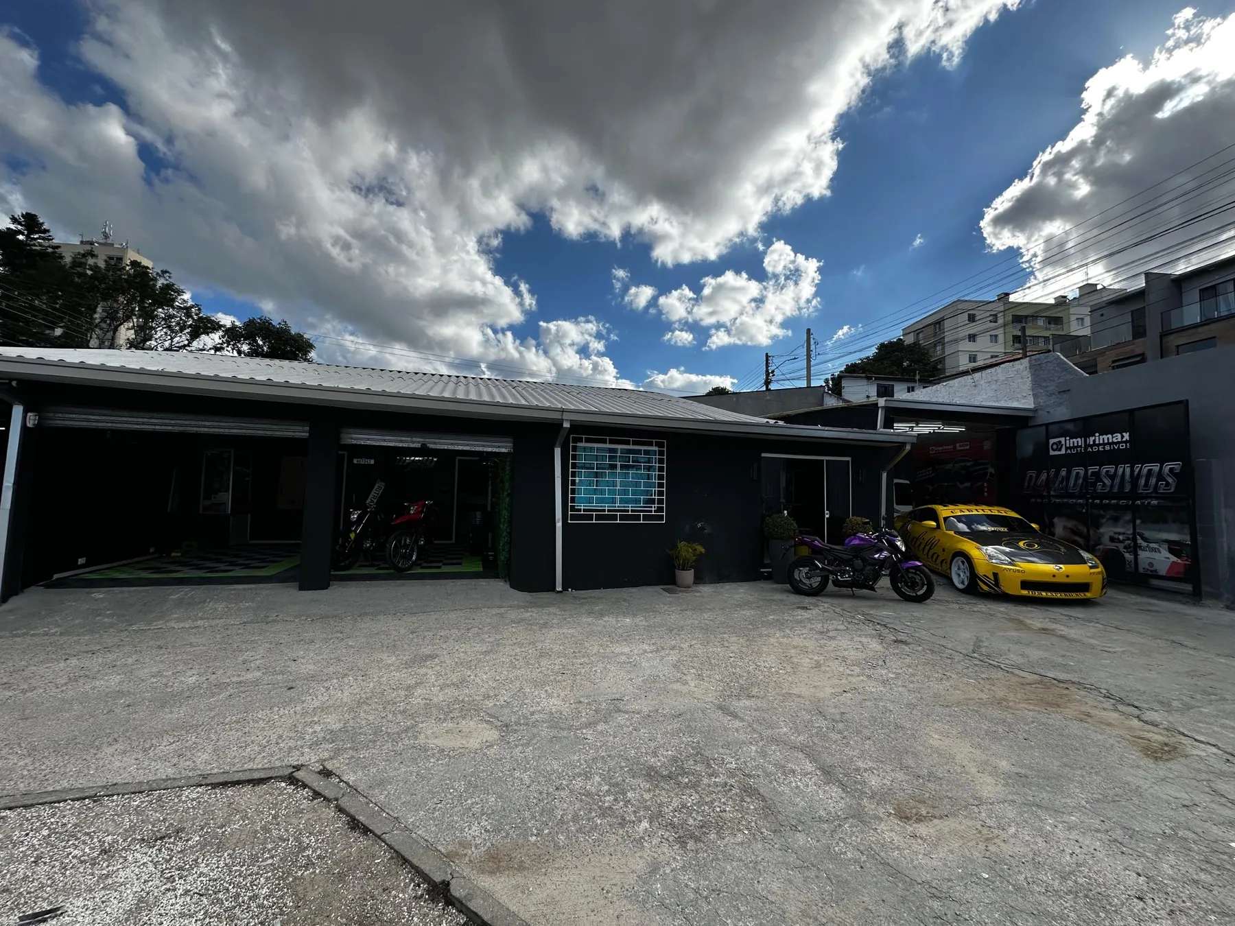 Fachada da loja 041 Adesivos com pátio, motos e carro esportivo