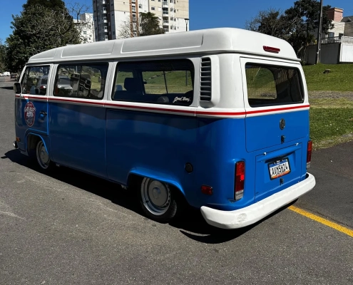 Kombi VW azul e branca rebaixada vista de três quartos traseiro