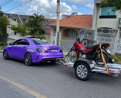 Mercedes CLA roxo metálico puxando reboque com moto vermelha