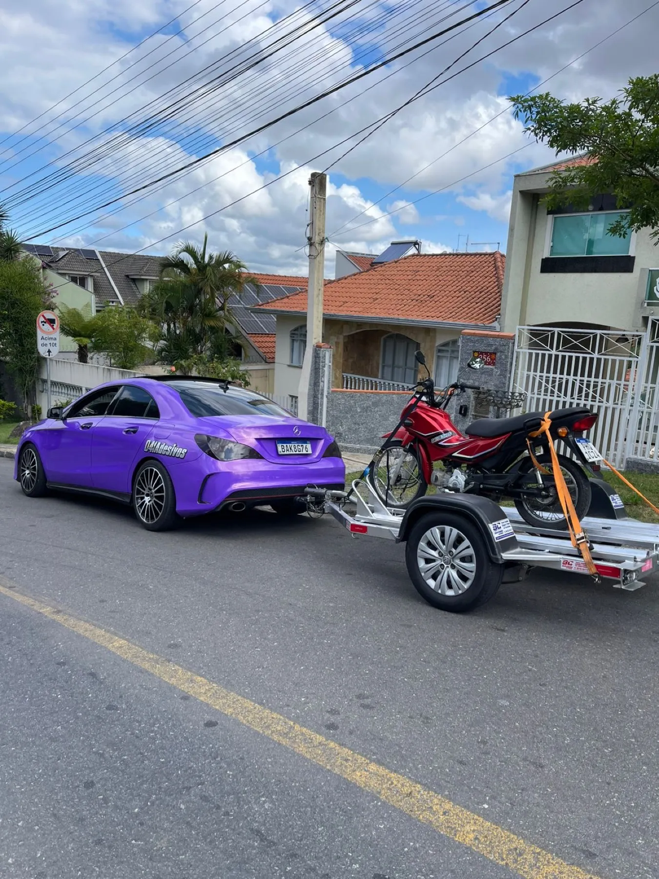 Mercedes CLA roxo metálico puxando reboque com moto vermelha