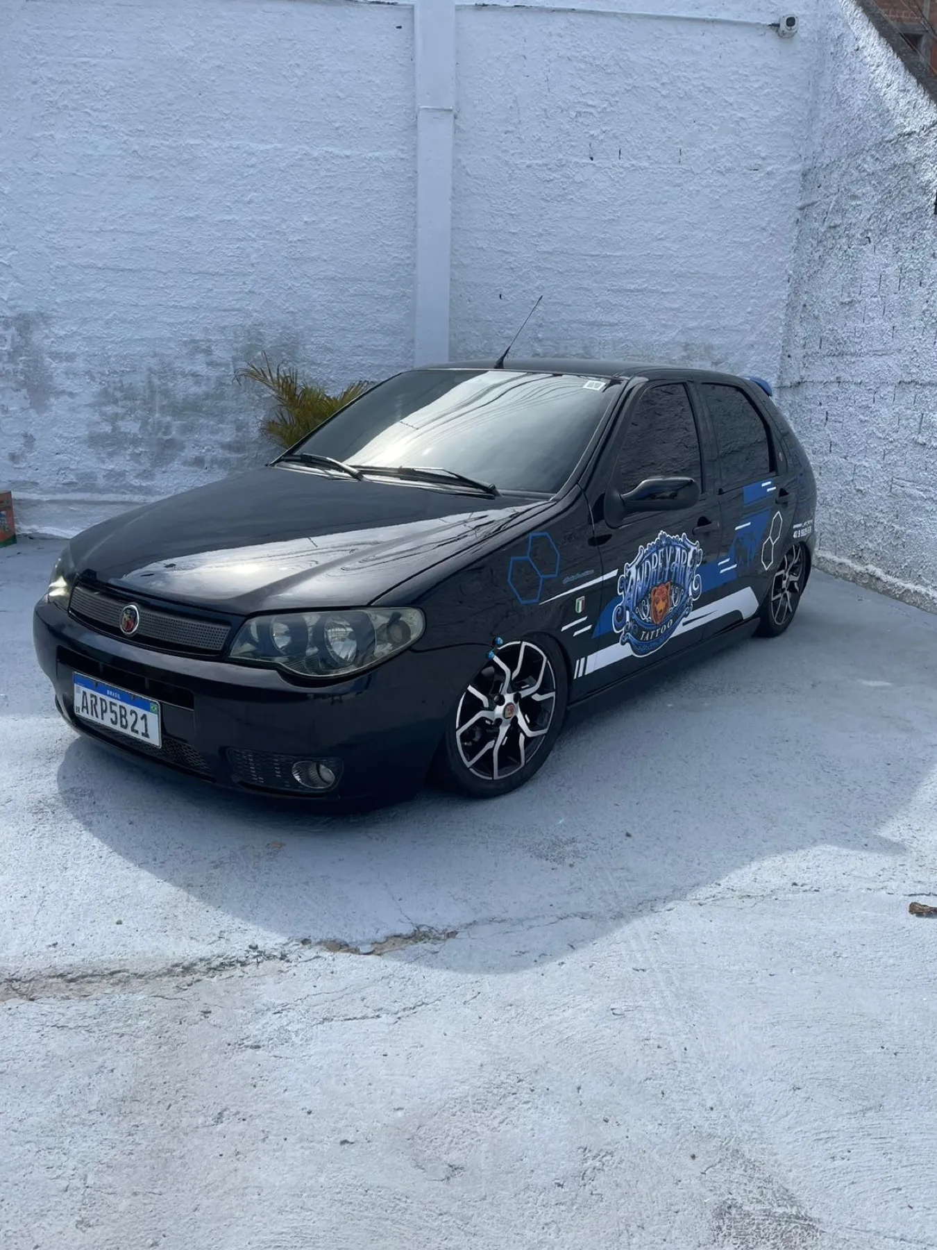Fiat Palio preto rebaixado com grafismo azul e escudo na lateral