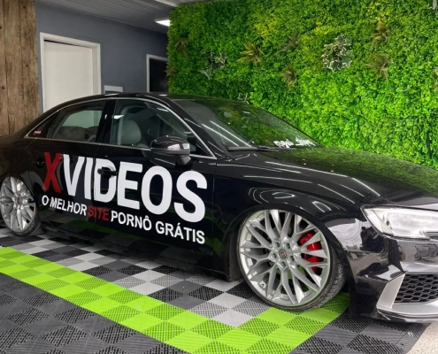 Audi sedan esportivo preto com plotagem de marca em garagem