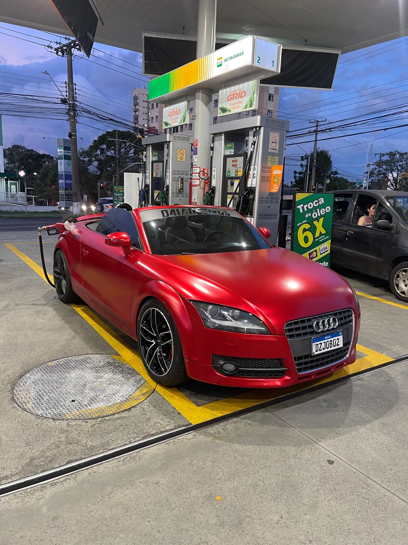 Audi TT Roadster vermelho fosco envelopado em posto
