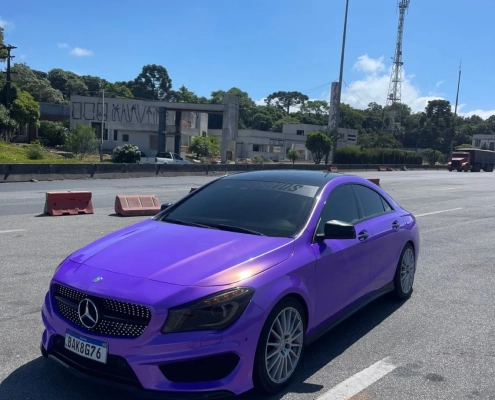 Mercedes-Benz CLA roxo envelopado, vista dianteira sob céu azul
