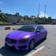 Mercedes-Benz CLA roxo envelopado, vista dianteira sob céu azul