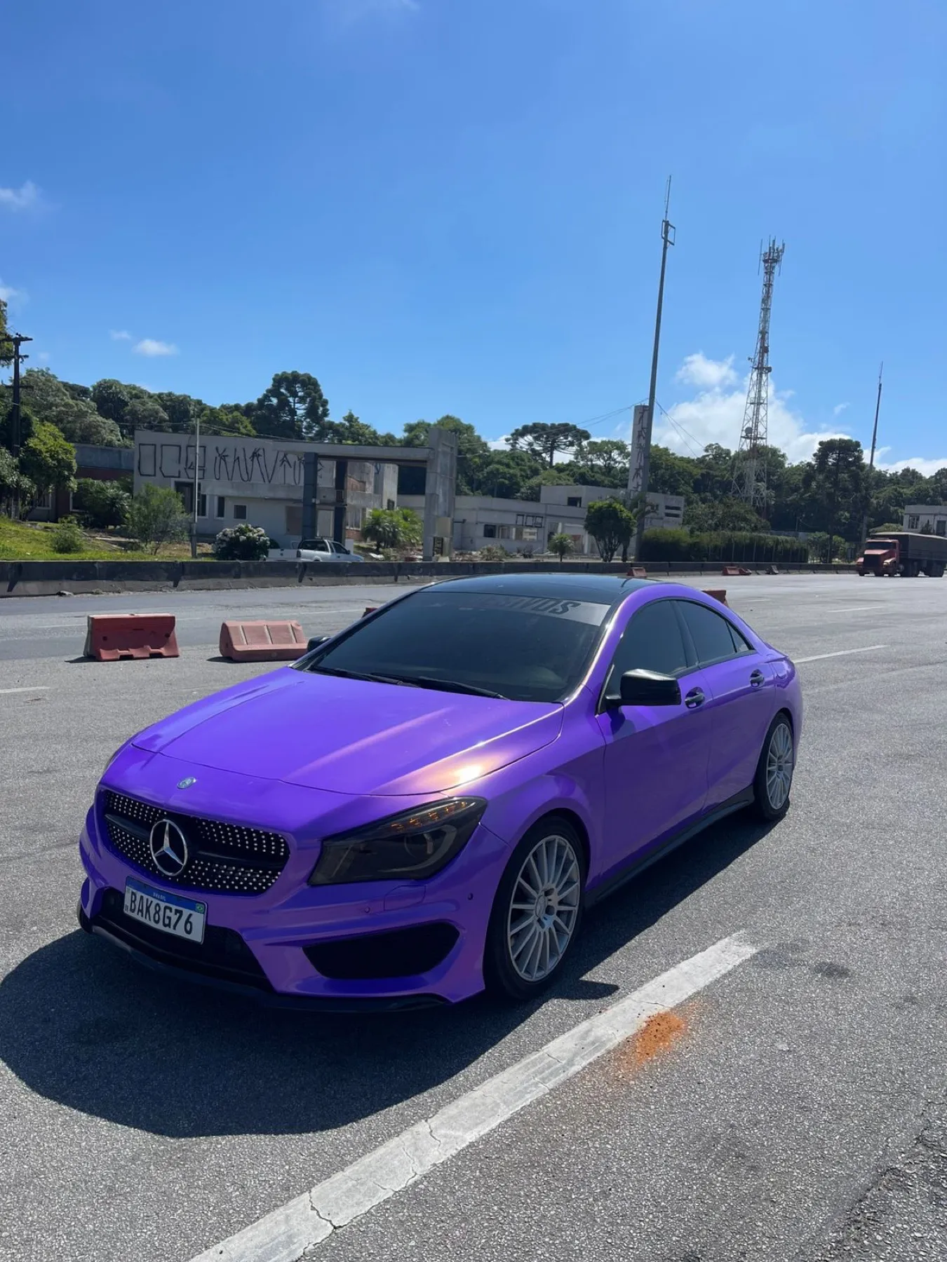 Mercedes-Benz CLA roxo envelopado, vista dianteira sob céu azul