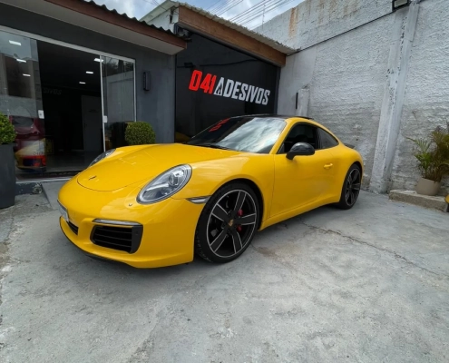 Porsche 911 amarelo em frente à fachada da 041 Adesivos