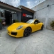 Porsche 911 amarelo em frente à fachada da 041 Adesivos
