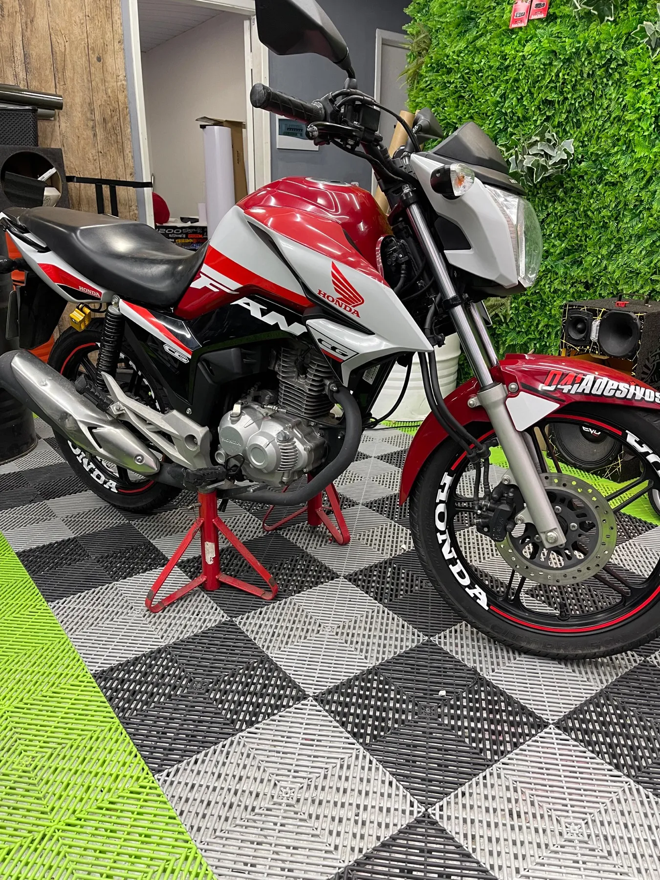 Honda CG Fan vermelha e branca com aro Honda na loja