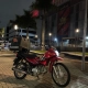 Honda Pop vermelha com baú adesivado em frente à Arena da Baixada