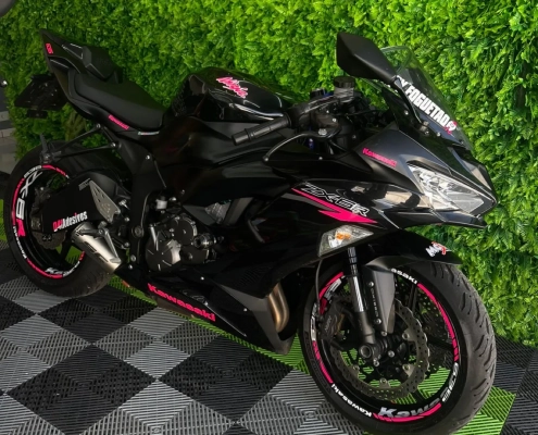 Honda trail preta e vermelha com adesivo no garfo